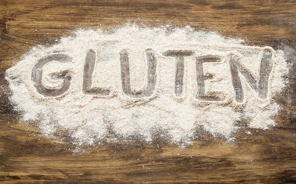 gluten word written in wheat flour on wooden board